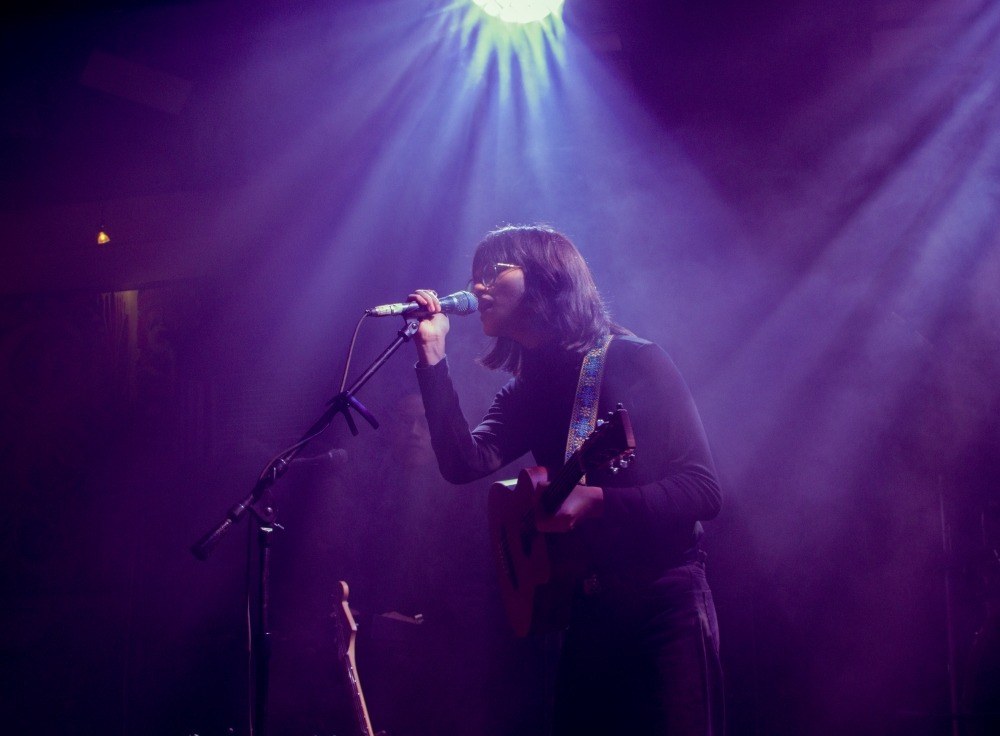 A singer performing under purple stage lights