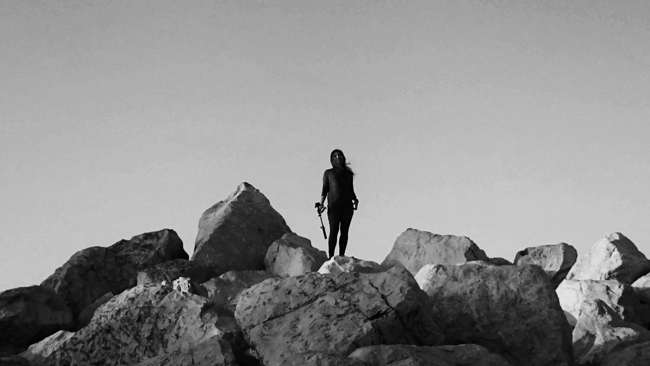 A person standing on rocks in a black-and-white landscape